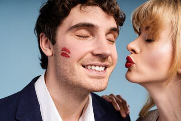 Elegant woman leaving lipstick kiss on smiling man