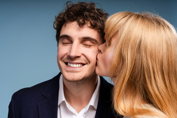 Man and woman kissing standing isolated on blue background