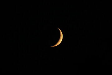Yellow crescent moon at night.