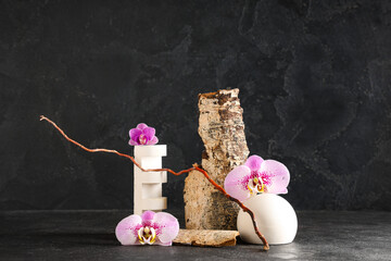 Decorative podiums and tree bark with beautiful orchid flowers on black background