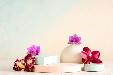 Decorative podiums with beautiful orchid flowers on light blue background