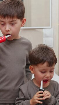 boy and baby child in bathroom,brushing teeth,washing hands with soap,combing hair.siblings,brothers in front of sink on tabouret chair.kids on toilet with lot of paper.