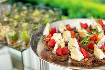 Canapes with brie cheese, raspberry and strawberries. The concept of restaurant service.