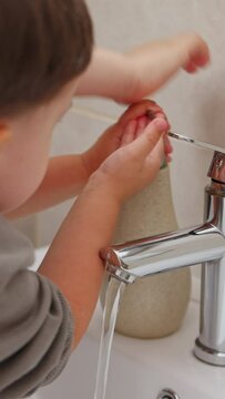 boy and baby child in bathroom,brushing teeth,washing hands with soap,combing hair.siblings,brothers in front of sink on tabouret chair.kids on toilet with lot of paper.