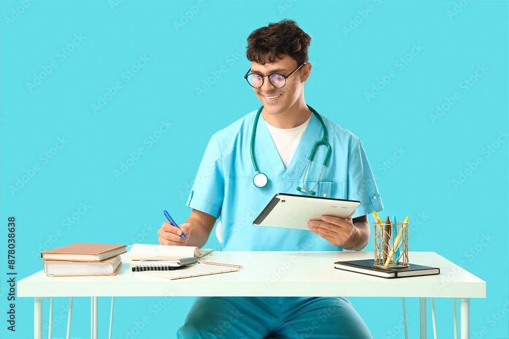 Poster male medical student with modern tablet computer and notebooks at table on blue background