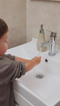 boy and baby child in bathroom,brushing teeth,washing hands with soap,combing hair.siblings,brothers in front of sink on tabouret chair.kids on toilet with lot of paper.