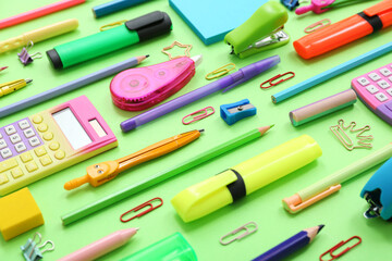 Pencils and different stationery on green background, closeup