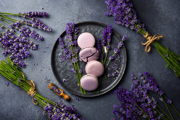 French macarons with lavender flavor and fresh lavender flowers, on a stone plate. Top view.