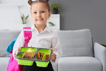 Little girl with school lunchbox at home