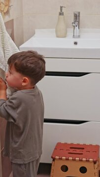 boy and baby child in bathroom,brushing teeth,washing hands with soap,combing hair.siblings,brothers in front of sink on tabouret chair.kids on toilet with lot of paper.