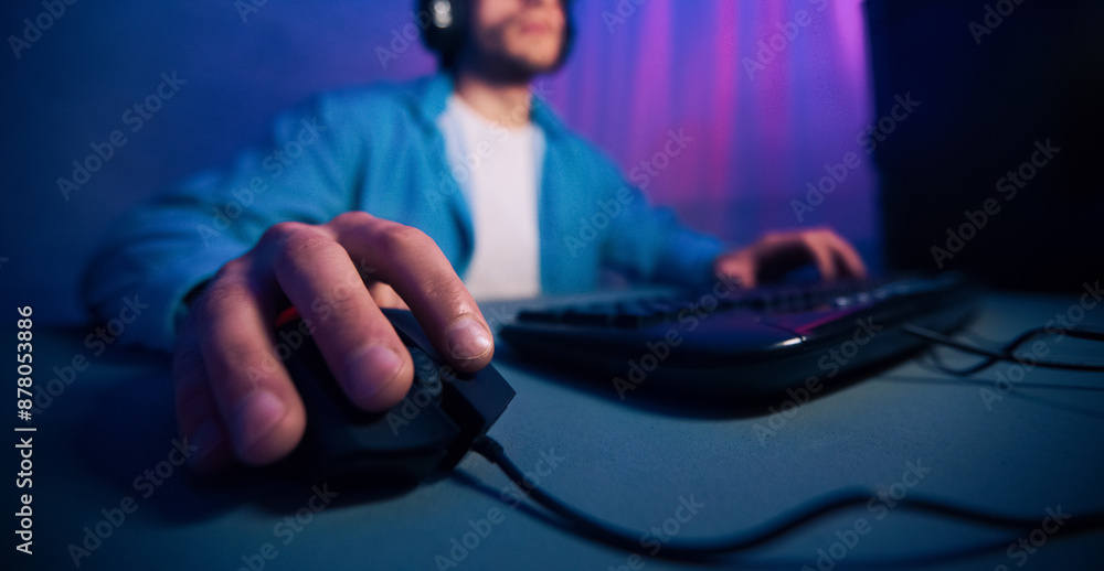 Fototapete A close-up image of a gamers hand using a computer mouse while playing a game on their desktop. The focus is on the hand and the mouse, cropped