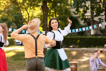 Young couple in traditional German clothes dancing outdoors. Octoberfest celebration