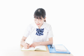机で勉強をする制服姿の女子学生