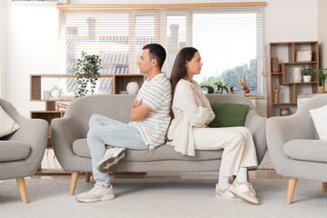 Offended young couple sitting on sofa at home