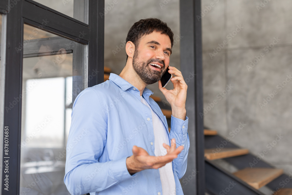 Aufkleber a man in a blue shirt stands near a glass door, smiling as he talks on a cell phone. he gestures wit