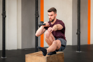 Strong man doing calisthenics kettlebell pistol squat exercise