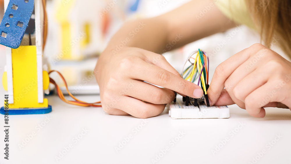 Poster A young person is shown working on a STEM project, connecting colorful wires to a breadboard. The image captures their focused concentration as they learn about electronics and circuits.