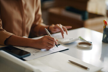 Close-up of woman working with logistic documents at her workplace