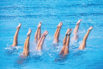 Artistic swimming team performing synchronized legs movement in swimming pool