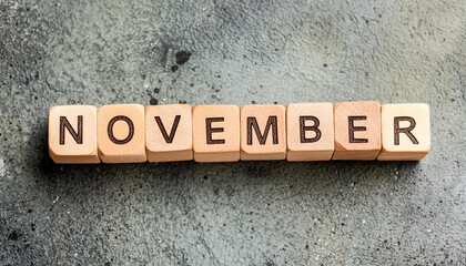 Obraz premium Wooden cubes with text NOVEMBER on dark cement backdrop. Autumn season. Month of year.