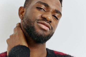 Man in red sweater with beard holding neck in pain or discomfort