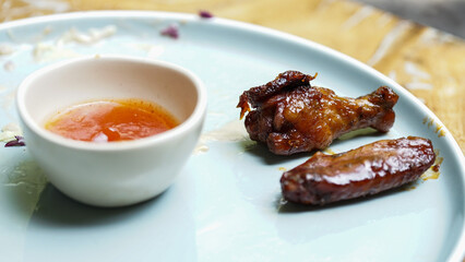 Sweet fried chicken wings with tomato chili sauce on a white ceramic plate