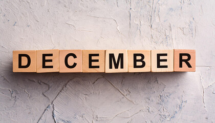 Wooden cubes with text DECEMBER on light cement surface. Winter season. Month of year. Close-up.