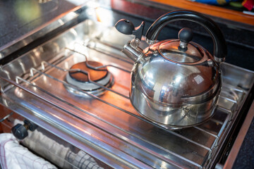 Kettle on gimballed gas stove in sailing yacht during yachting