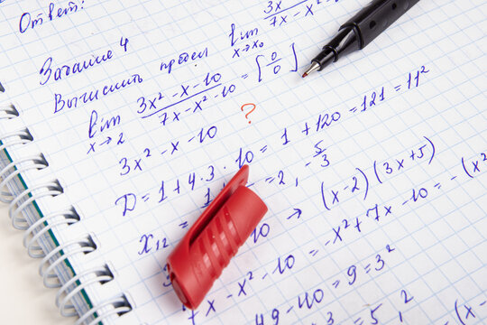 Learning mathematics. Calculating the mathematical limit. Checking homework with red pen. "Calculate the limit"