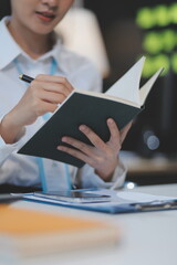 Cheerful businesspeople using a laptop in an office. Happy young entrepreneurs smiling while working together in a modern workspace. Two young businesspeople sitting together at a table.