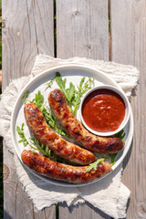 Three hot dogs are on a white plate with a side of ketchup