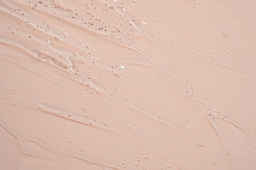 A creamy white substance is spread across a light pink background