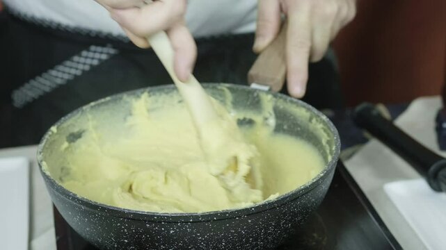 Chef mixes dough batter mixture on stove to prepare to make panelle or panella