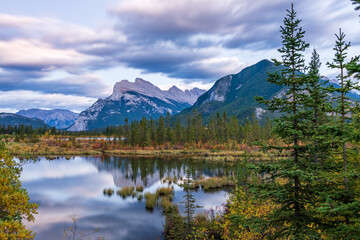 Vermilion Lakes autumn foliage scenery in dusk. Banff National Park, Canadian Rockies, Alberta, Canada. Colorful trees in orange, yellow, golden colors. Mount Rundle, Sulphur Mountain in background.