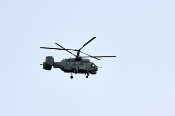 Russian military helicopter armed with missiles flies in blue sky, airborne mission of gunship with targeting system performs an aerial maneuvers for military operation, russian aviation