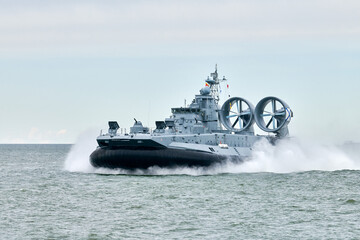 Hovercraft warship armed with armament sails into sea toward military target to attack and destroy enemy, military hovercraft ship performing strategic maneuver, Russian sea power deployment © TRAVELARIUM