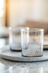 Two glasses on a tray with a gray background