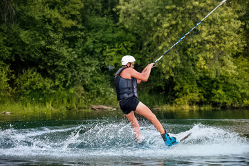 A man wakeboarding on a lake on summer day in a life  jacket. Soft focus. Action blur.