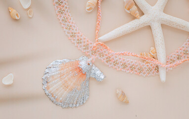 Close up on a pendant necklace made of a clam and beads surrounded by small seashells and starfish