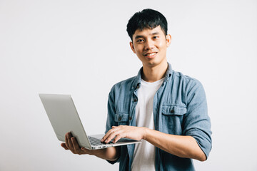 Portrait of a happy Asian student, excited and confident, using a laptop for email or chat. Studio shot isolated on white, showcasing his success in the online world.