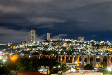 Night View of Illuminated Aqueduct of Queretaro Against a Modern Cityscape