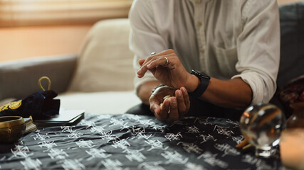 Fortune teller with shells in hands forecasting future for client in dark room. Divination concept