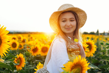 Female Farmer Holding A Bottle Of Sunflower Oil Against A Background Of Sunflowers. The Concept Of...