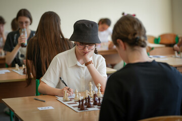 The girl plays chess in club, leisure activity of weekend and compitetion concept. Pieces on the chessboard. Chess game, close-up, portrait. Chess tournament, competition