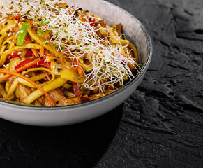 Spicy asian noodle dish with sprouts on dark background