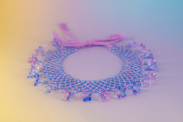 Beautiful lilac and pink necklace made of beads with floral pendants on multicolored background