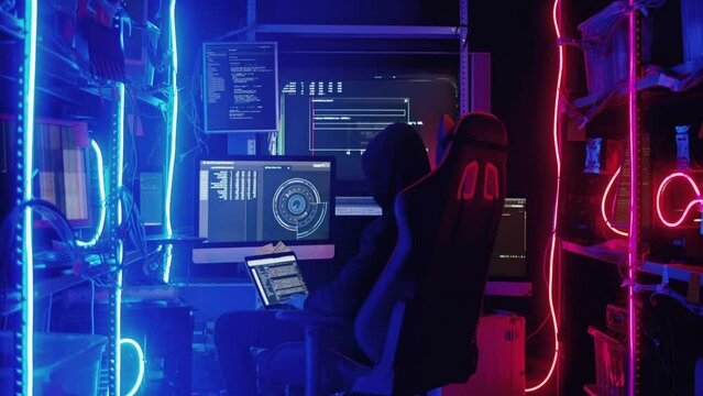 Back View of Teenage Hacker Working in Computer and Infecting with Virus Data Servers of Government Infrastructures.
