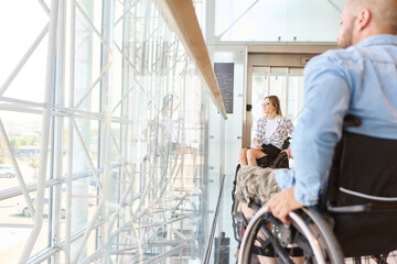 Obraz premium People in wheelchairs enjoying the view in a modern sunlit building