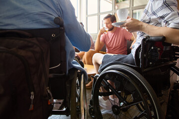 Social gathering featuring person in a wheelchair enjoying coffee with friends