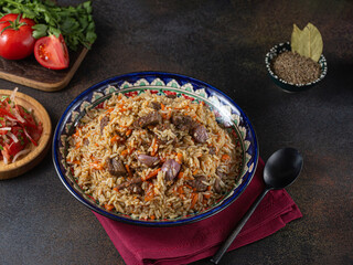 The concept of oriental cuisine. National Uzbek pilaf with meat in a cast-iron skillet, on a wooden table. background image. top view, copy space, flat lay